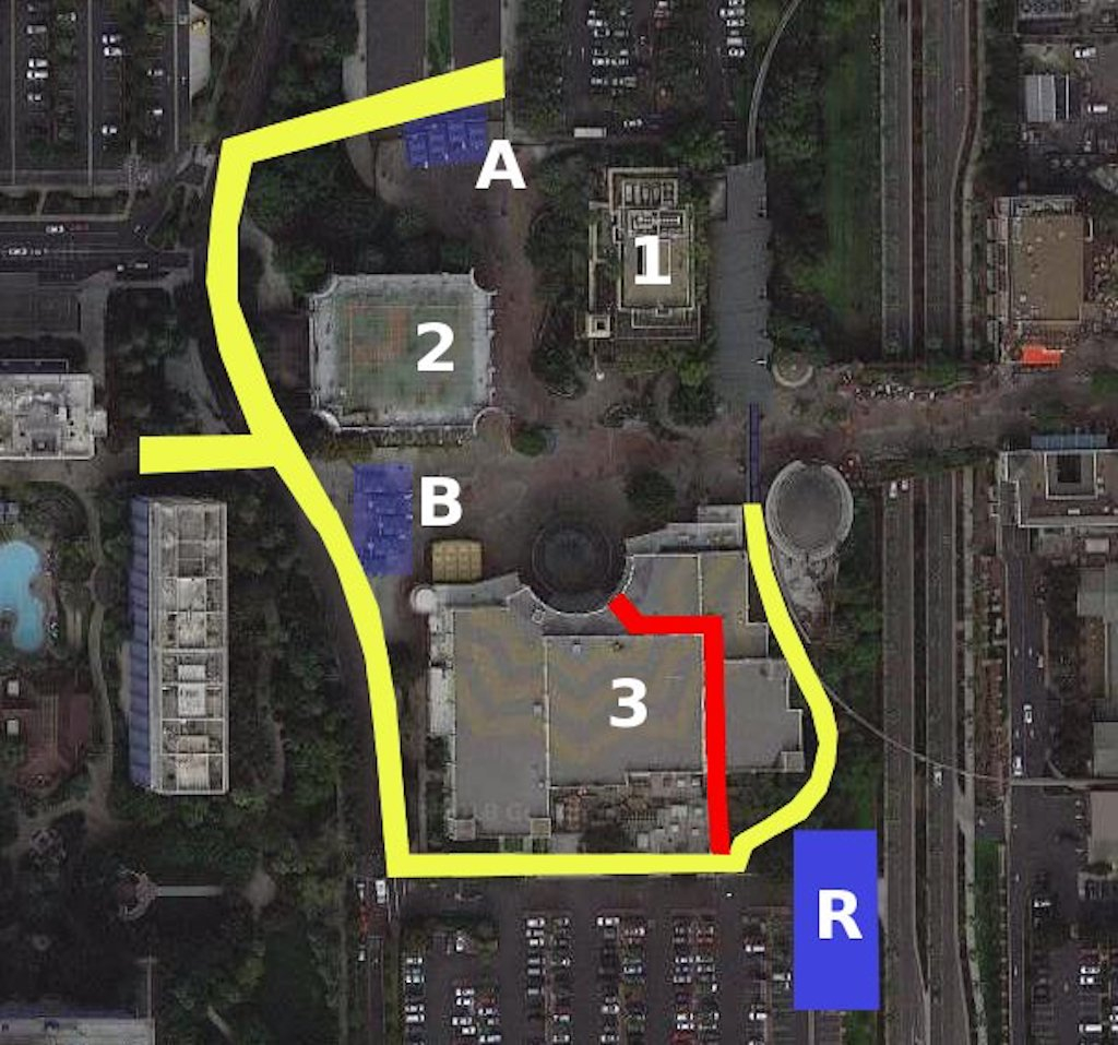 Diagram of Downtown Disney Anaheim’s west end. “A” marks the location of the Downtown Disney parking lot security gate. “B” is the hotel security gate. “R” is the general area of the former Richfield gas station. Also: 1, Rainforest Café; 2, ESPN Zone, and 3, AMC Theater complex. The yellow path marks the proposed route to take guests around the AMC Theater and through the former cast entrance between AMC and the Lego store. The red path shows a route through the east end of the former AMC Theater complex, avoiding the Richfield Gate work area.