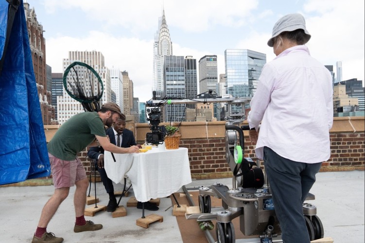 Animal wrangler Tim Cockerill wrangles bugs on a rooftop table near actor Fazon Gray in New York City, N.Y. during a shoot for 'The Big City' episode of 'A Real Bug's Life.' Grip Heidi Grunwald stands off to the right of the frame. (National Geographic/Joe Craig)